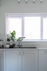 Modern new kitchen with light grey furniture and quartz worktop, light interior trendy units. Granite sink under big window