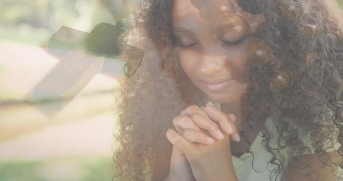 Animation of biracial girl praying and rosary in background