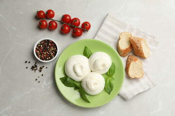 Delicious burrata cheese with basil served on light table, flat lay