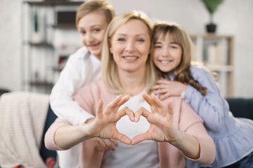 Portrait of little happy girl and boy and mother join hands forming heart shape as concept of giving love, child mum connection unity, cute kids and mom bonding looking at camera, child care adoption