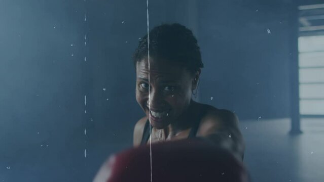 Animation of interference over african american female boxer punching at gym - Powered by Adobe