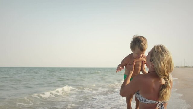 Mom throws her son up over the sea on summer vacation under the warm sun