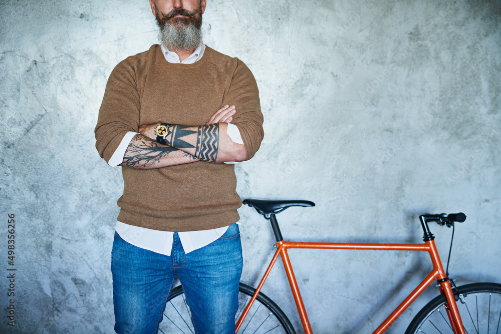 Poster he is going places. studio shot of a middle aged man standing with his arms folded with a red bicycl