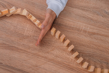 hand with wooden pieces and domino effect