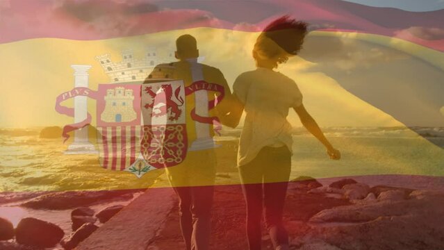 Animation of flag of spain over african american couple at beach