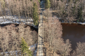 Road through the forest. Winter landscape over the forest Photo from a drone. Scandinavia. Finland.