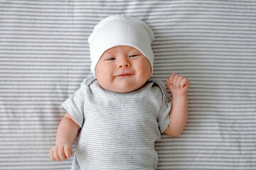 A cute newborn baby laying on a nappy smiling at the first time. First smile. Baby care and growing.