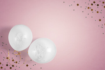 White party balloons and table confetti on a pink background with copy space