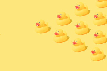 Pattern made of rubber bath ducks on yellow background. Copy space.