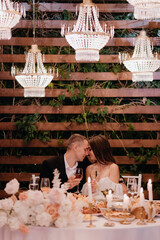 A young couple is sitting at a table at a wedding in the evening. 