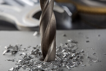 metal drill bit make holes in aluminium plate on industrial drilling machine. Metal work industry.