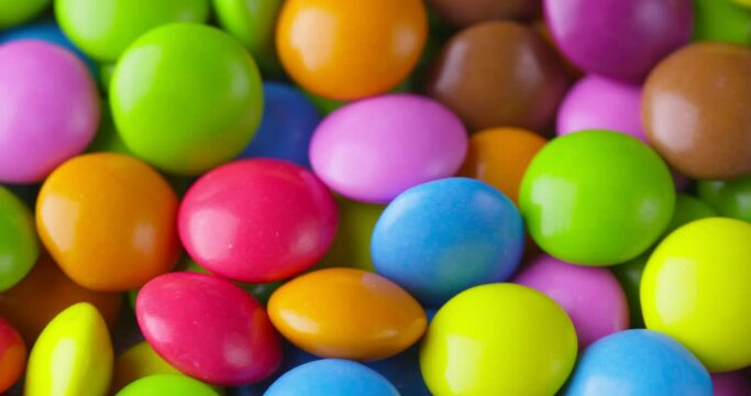 Slow motion close-up of round colorfull chocolate candies, dragee. Rotation and fall multicolored chocolate candies