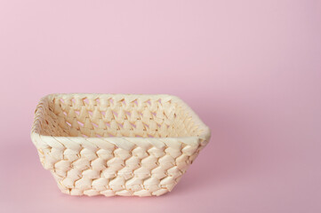 Rectangular empty wicker basket on a pink background. Side view. Decorative interior items. Products made from natural materials. Copy space. Selective focus