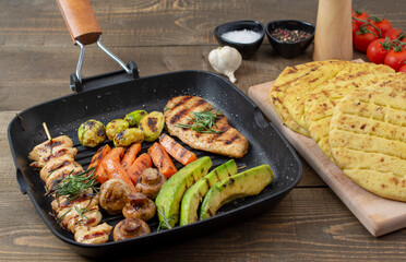 Grilled chicken breast with different  vegetables on teflon pan.