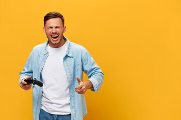 Irritated evil tanned handsome man in blue basic t-shirt angry about losing hold joystick gamepad...