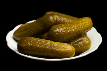 Salted, pickled cucumbers in a white plate on a black background