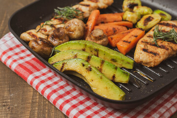 Grilled chicken steakand souvlaki in different variations with avocado, carrot, mushroom and brussels sprout on a teflon pan.