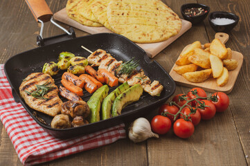 Grilled chicken breast and souvlaki  with different vegetables in a pan.