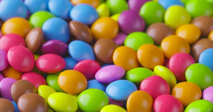Slow motion close-up of round colorfull chocolate candies, dragee. Rotation and fall multicolored chocolate candies