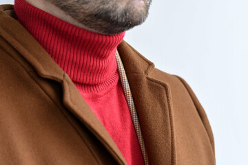 Detail of men outwear, fashionable mens brown coat combined with red sweater and light beige blazer. Selective focus.