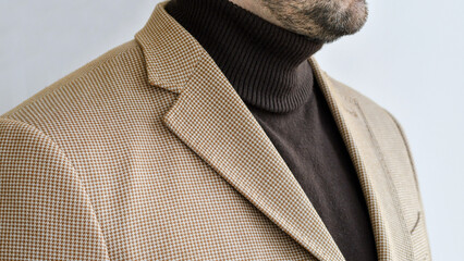 Detail of men outwear, light beige blazer combined with dark brown sweater. Selective focus.