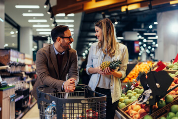 Young happy couple with the cart shopping in supermarket