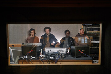 Graphic portrait of diverse music band composing new album in professional recording studio behind...