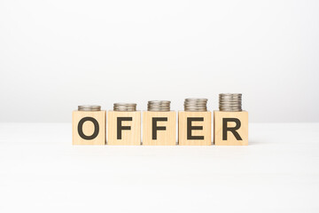 offer text written on wooden block with stacked coins on white background