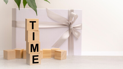 Obraz premium Time word made with building blocks on the table next to a flower and a gift box