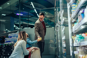 Parents and daughter buying groceries in market together