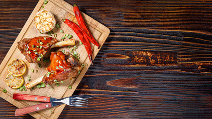 Chicken drumsticks with garlic and spices on a wooden board, top view, copy space