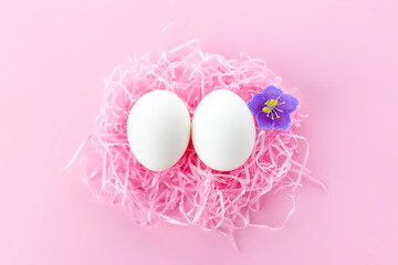 Easter background.Funny eggs in the nest and flowers. Postcard with space for text in pink, toned