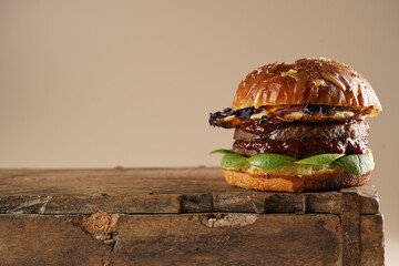 Hamburger with double angus beef patty, tomatoes, spinach, fried egg and barbeque sauce on wooden...