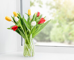 a bunch of tulips in a vase on the windowsill
