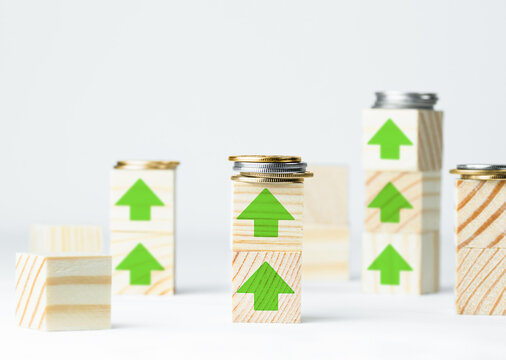 Wooden Cubes With Coins And Painted Green Upward Arrows, The Concept Of Growth And Rise On A Light Gray Background, The Concept Of Profit Growth