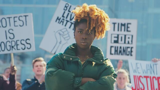 Portrait of female protestor surrounded by marchers holding placards and chanting slogans on demonstration march to promote awareness of black lives matter and racial equality - shot in slow motion
