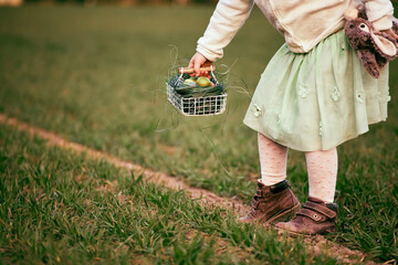 Cute caucasian pre-schooler blonde girl at Easter egg hunt by grandma's country house, outdoor