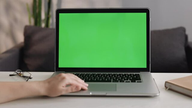Close up shot of unrecognizable woman hands of freelancer working with mockup chroma key green screen laptop using trackpad scrolling through website - technology concept 4k video template