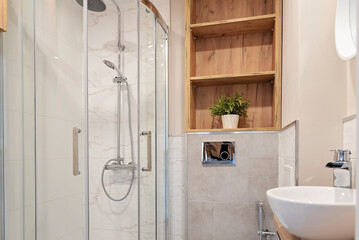 Small bathroom with cabin and shower and modern bathroom sink on the wooden counter. Luxury in...