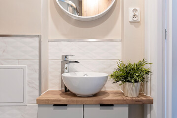 Ceramic bathroom sink with faucet on wooden counter. Interior of small bathroom with white tiles on...