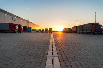 Obraz premium Logistics area with halls and trucks at sunset. Transport and storage of goods.