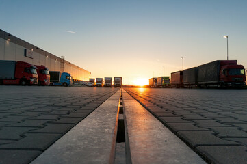 Logistics area with halls and trucks at sunset. Transport and storage of goods. © Jan