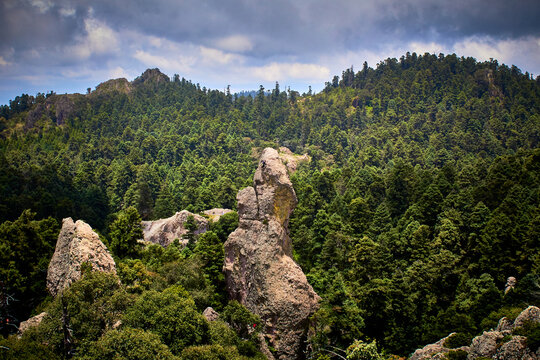 formaci&oacute;n rocosa, para escalar saliendo de un bosque de coniferas con un cielo nublado color gris oscuro en mineral del chico, Hidalgo 