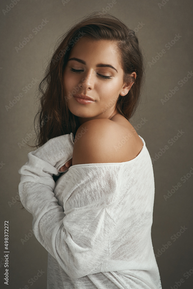 Wall mural True beauty is effortless. Shot of a beautiful young woman smiling against a brown background in studio.