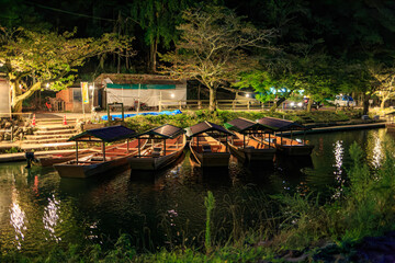 Fototapeta na wymiar River tour boats sit idle along river in Kyoto at night