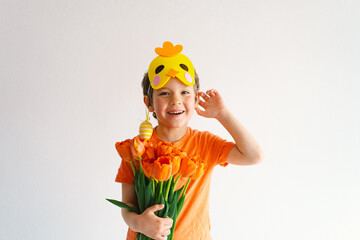 Funny boy with orange tulips and in the mask of a chick on white background. Children celebrating Easter. Happy easter card