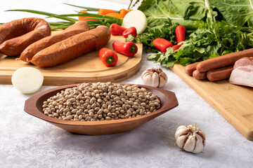  ingredients for preparing a recipe, dried meat, bacon, cabbage, red bell pepper, sausage, parsley, on a table
