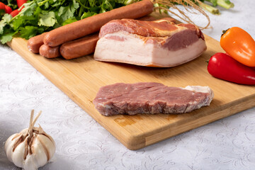  ingredients for preparing a recipe, dried meat, bacon, cabbage, red bell pepper, sausage, parsley, on a table