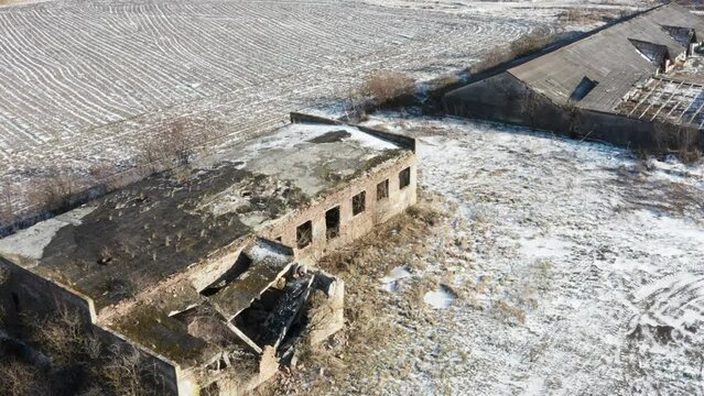 Aerial view of an abandoned industrial building near the agricultural field. Winter time