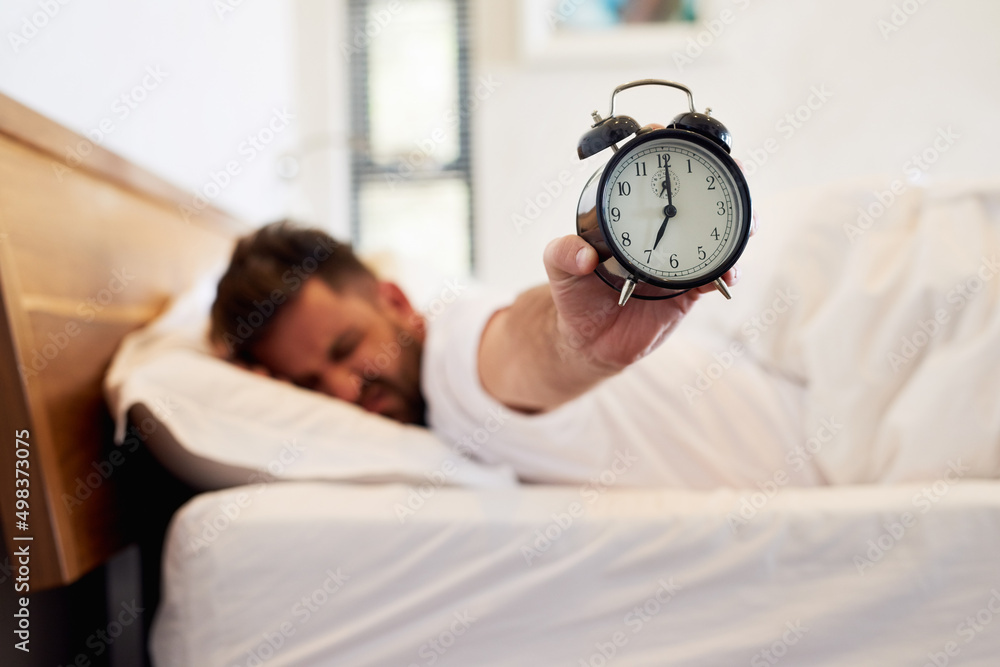 Aufkleber time to face the day. cropped shot of a young man holding up an alarm clock while waking up from bed